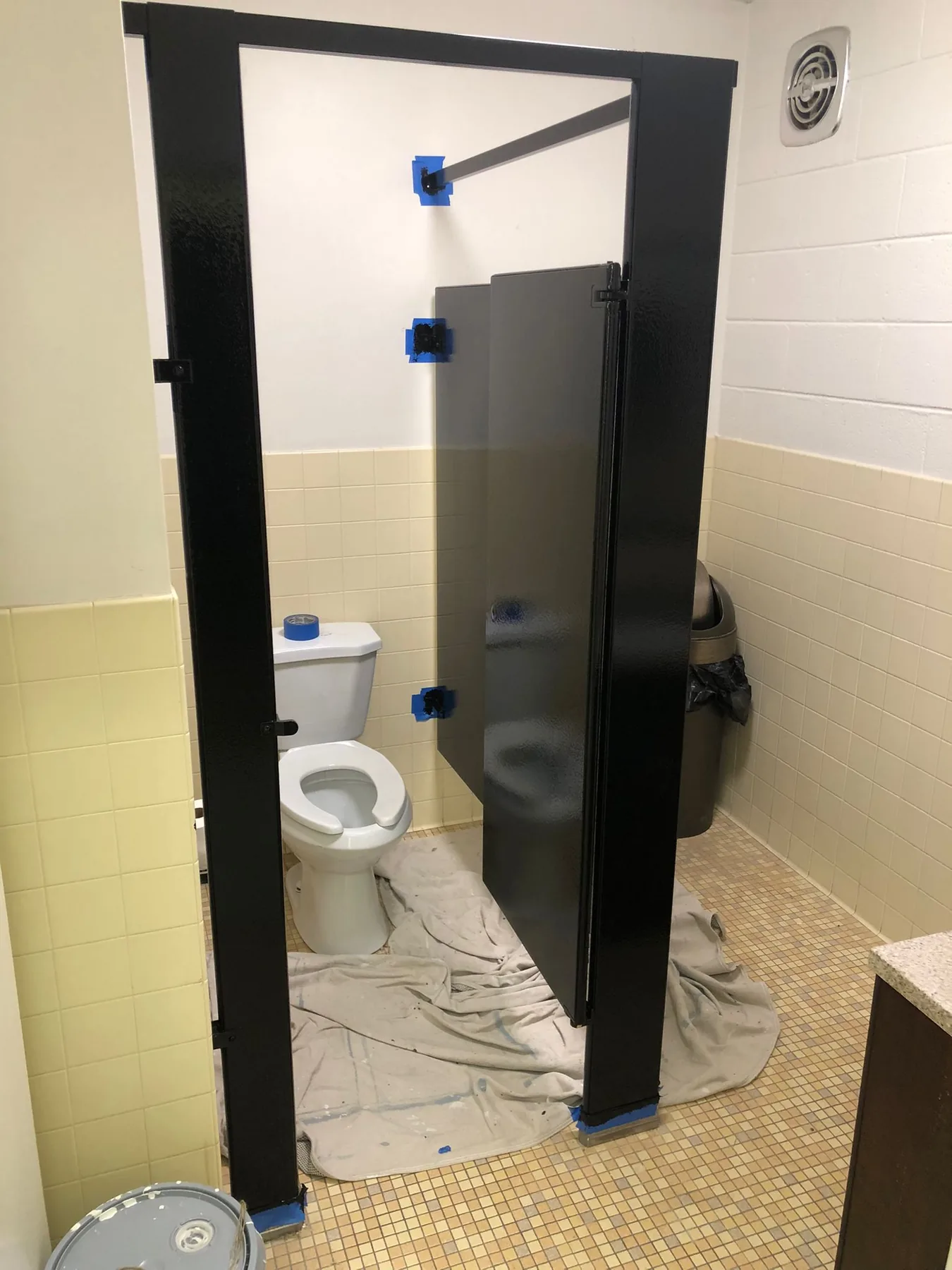 Commercial restroom partitions protected and being repainted
